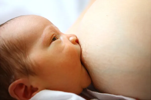 Baby saugt Mutter die Brust lizenzfreie Stockbilder