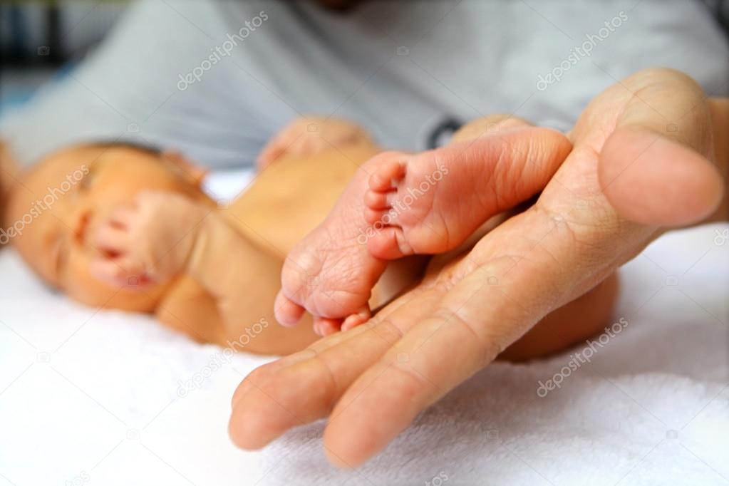 Baby's legs in father's hands