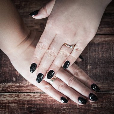 Ahşap arka planda siyah tırnaklı kadının bling-bling etkisi. Parlak efekti seveceksin.