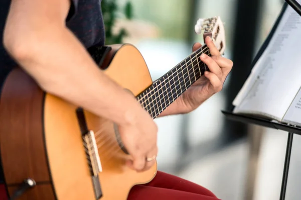 Male musician playing guitar, music instrument. Man\'s hands playing acoustic guitar, close up. Acoustic guitars playing. Music concept.