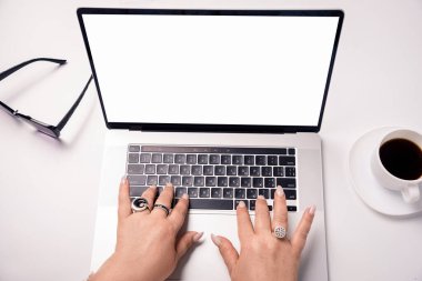 close-up of female hands on a laptop with a white screen for an inscription