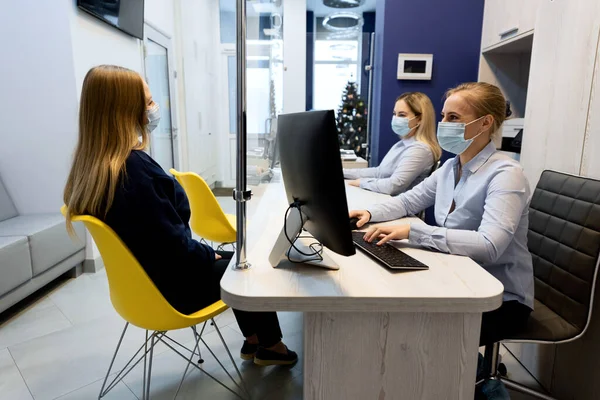 two girls in masks receive clients at the reception
