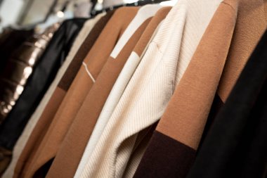 Women's minimalist fashion pastel clothing. Stylish women's blouses, sweaters, t-shirts on a hanger. Fashion blog, website, social media hero header.