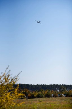 a small plane flies high above the field
