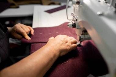 Women's hands sew pieces of fabric on a sewing machine close-up. horizontal frame