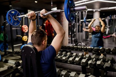 Profesyonel sporcu ile bir halter onun omuzlarında oturur ve onunla durmak hazırlar. Arkadan görüntülemek.