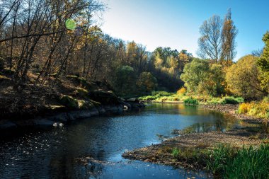 autumn landscape with a view of the river, trees, stones and sky