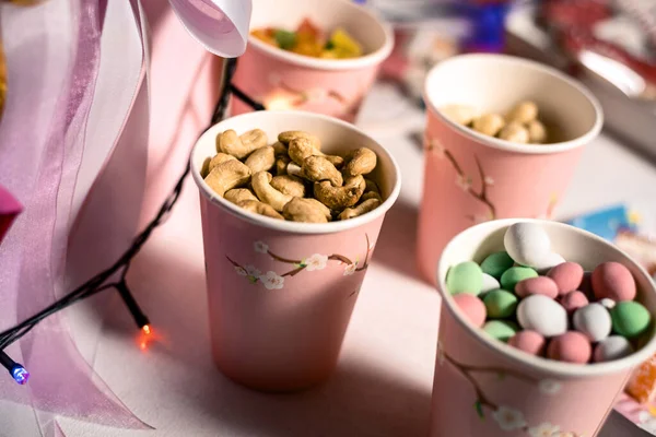 cashews, sweet balls in pink paper cups