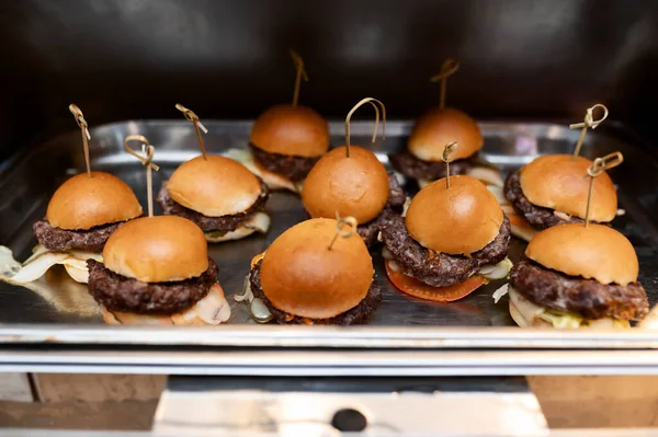 Mini hamburgers, burger and hot dogs with yellow mustard on the kitchen counter