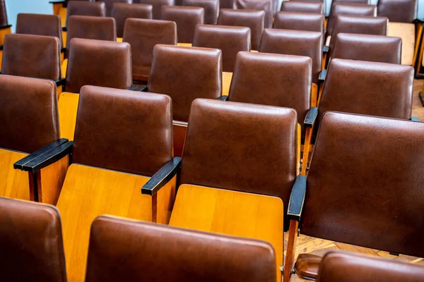 a lot of old brown chairs for the whole frame, seats for spectators