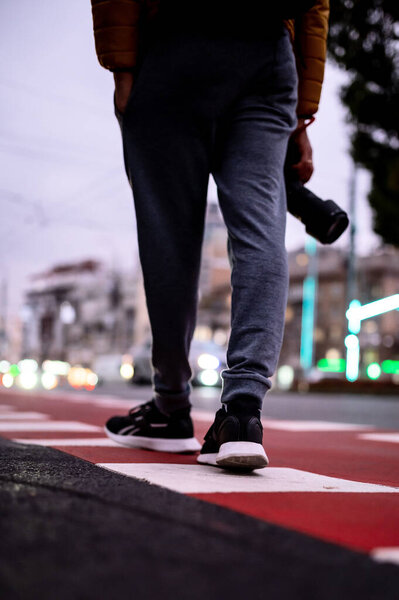 close-up of legs in sneakers on a crosswalk
