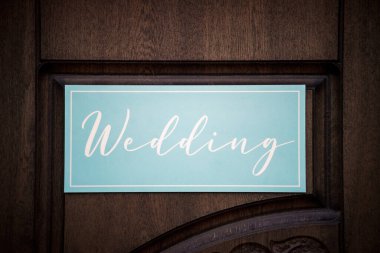 Bir ok şeklinde mavi bir levha ve üzerinde İngilizce yazılar ve yazılar olan bir işaretçi törende doğada duruyor..