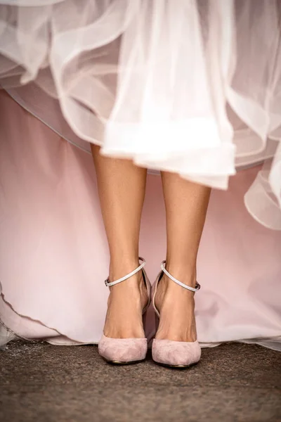 beautiful legs of a girl in shoes stand in a pink dress