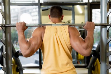 Halter çömelmesi yapan yakışıklı, güçlü bir atletik. Mükemmel kasları olan güçlü bir vücut geliştirici.