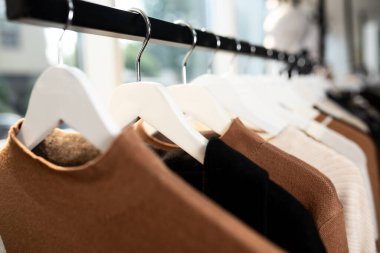Women's minimalist fashion pastel clothing. Stylish women's blouses, sweaters, t-shirts on a hanger. Fashion blog, website, social media hero header.