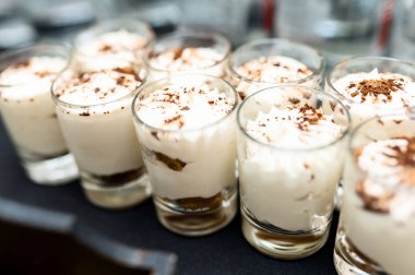 Ufalanmış çikolatalı kurabiye ve peynirli kek gezegendeki rustik bir arka plan karşı üç bardak. Tatlı önünde tarih seçici odak ile alan aşırı sığ derinliği.