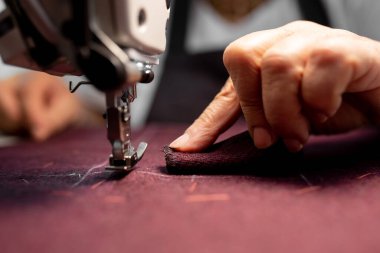 Women's hands sew pieces of fabric on a sewing machine close-up. horizontal frame