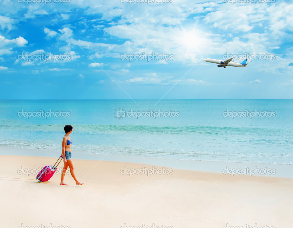 Woman with a suitcase on the beach