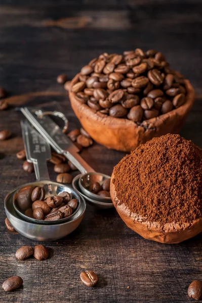 Ceramic bowl with coffee beans and ground coffee on a wooden background