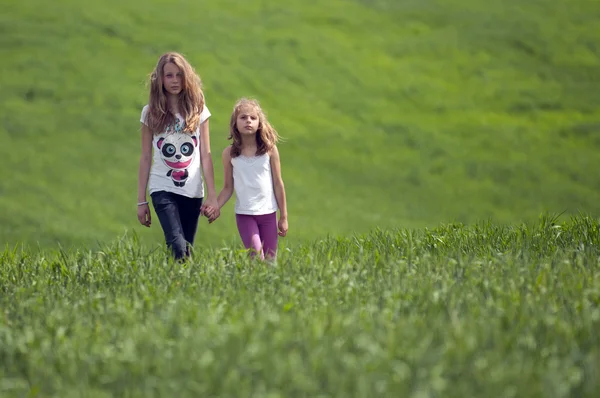 Duas meninas em um campo verde — Fotografia de Stock