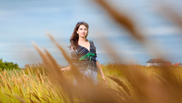 Mladá bruneta žena chůze přes slunné žlutá podzimní pole — Stock fotografie