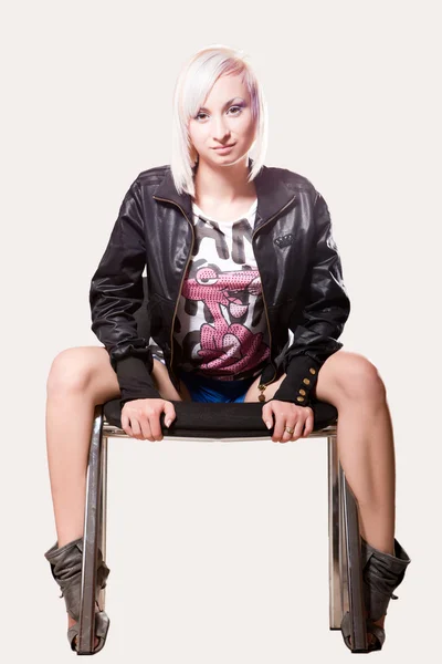 Young happy woman sitting on a chair over a light background Royalty Free Stock Photos
