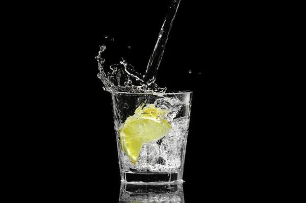 Espalhe em um copo com limão e gelo em um fundo preto — Fotografia de Stock