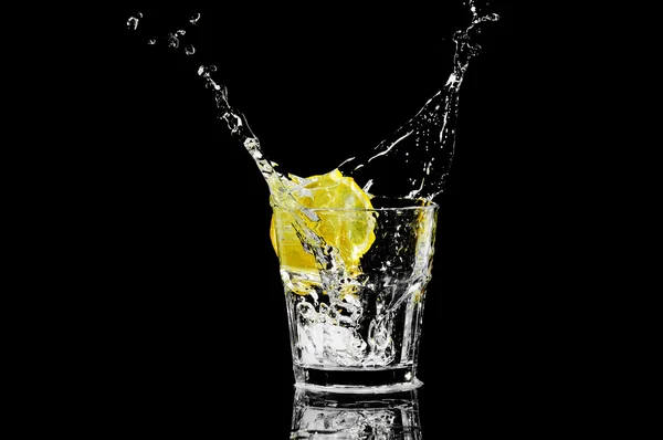 Versez dans un verre avec du citron et de la glace sur un fond noir Image En Vente