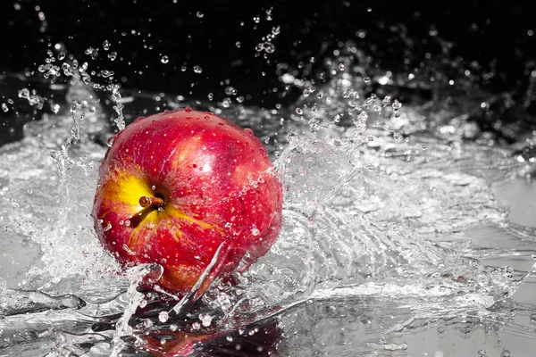 Fresco uma maçã em água respingo de streaming no fundo preto — Fotografia de Stock