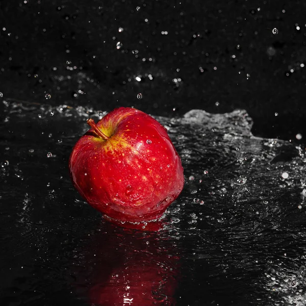 Fresh an apple in streaming splash water on black background — Stock Photo, Image