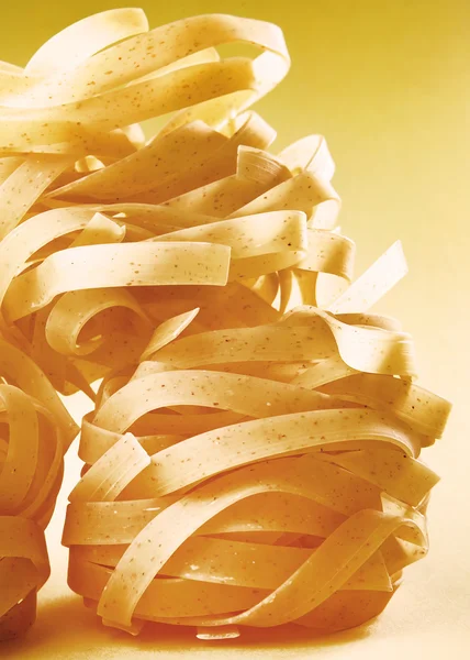 Italian pasta fettuccine on yellow gradient surface. — Stock Photo, Image