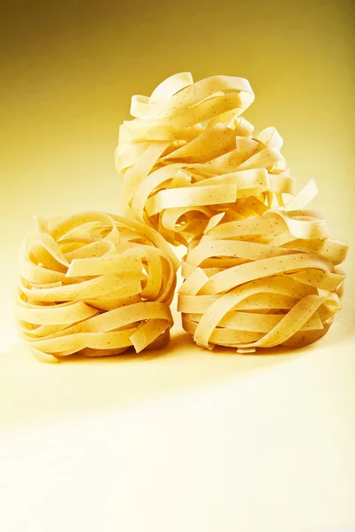 Italian pasta fettuccine on yellow gradient surface. — Stock Photo, Image