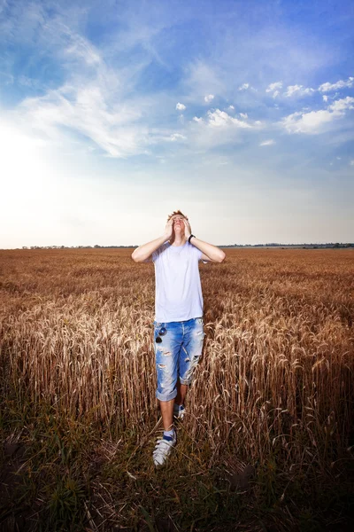 Feliz hombre de pie con los brazos cerrados en un campo de trigo — Foto de Stock