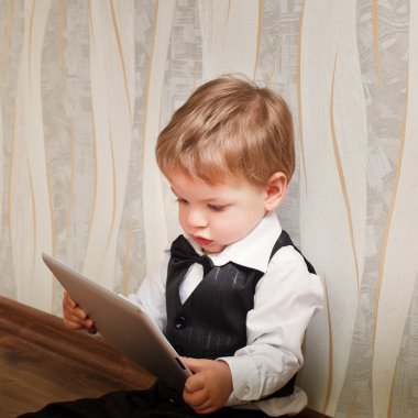 küçük çocuk bir takım elbise ve papyon tablet bilgisayar okur