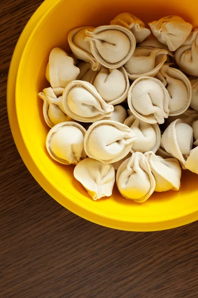 Fleischknödel - russische rohe Pelmeni im Teller auf Holzhintergrund — Stockfoto