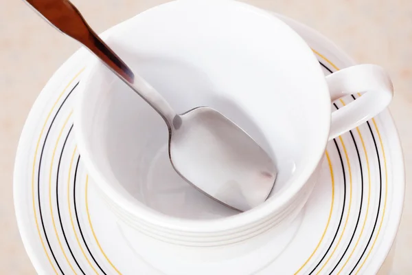Xícara de chá e pires com uma colher em um fundo branco — Fotografia de Stock