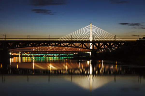 Beleuchtete Brücke in der Nacht und spiegelt sich im Wasser — Stockfoto