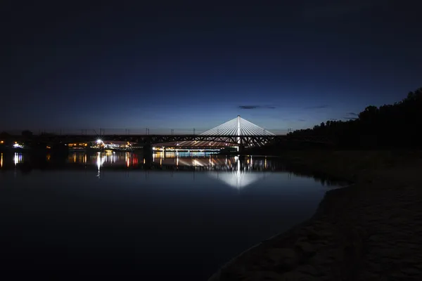 Beleuchtete Brücke in der Nacht und spiegelt sich im Wasser — Stockfoto