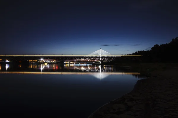 Pont en surbrillance la nuit et reflété dans l'eau — Photo