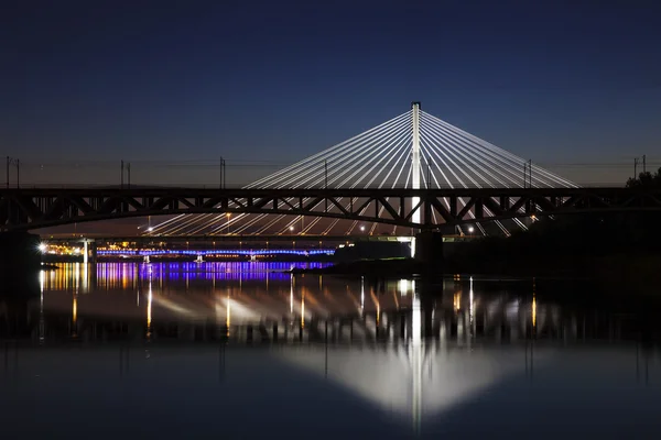 Подсвеченный мост ночью и отраженный в воде — стоковое фото