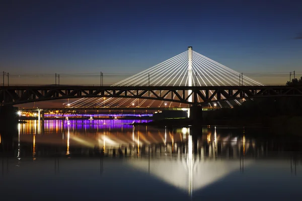 Backlit brug bij nacht en gereflecteerd in het water — Stockfoto