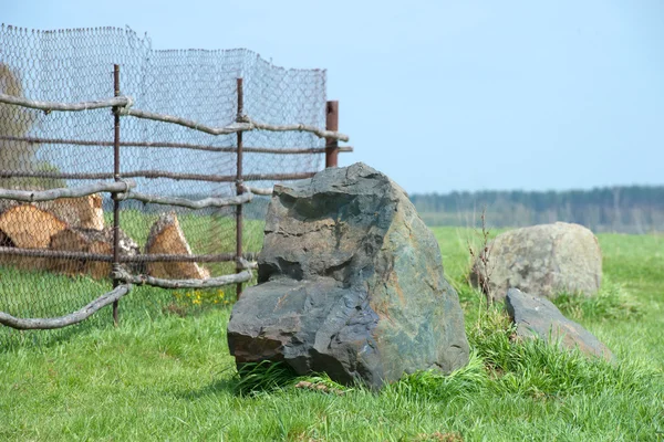 Stor svart sten stänger vägen till staketet — Stockfoto