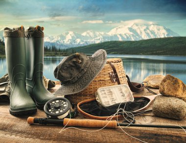Fly fishing equipment on deck with view of a lake and mountains clipart