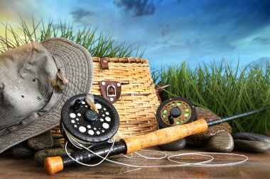 Fly fishing equipment with hat on wooden dock clipart