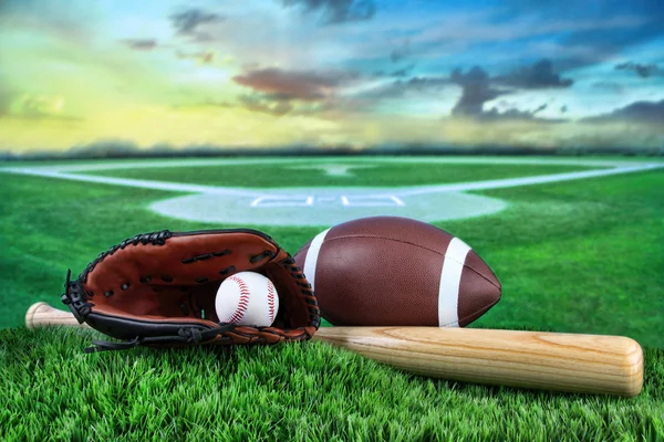 Baseball, Schläger und Handschuh im Feld bei Sonnenuntergang — Stockfoto