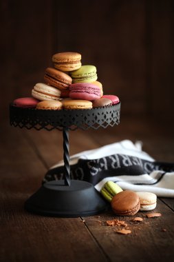 Cake stand with macaroons on dark wood background clipart