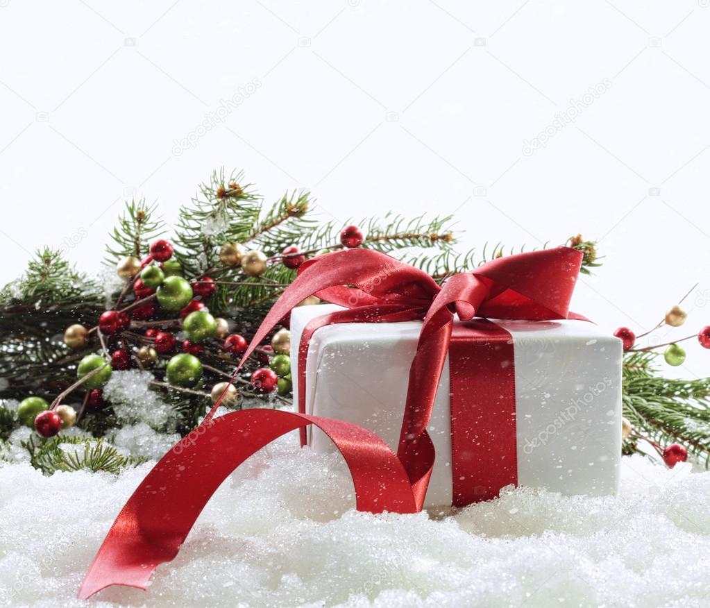 Gift box with red ribbon in snow on white