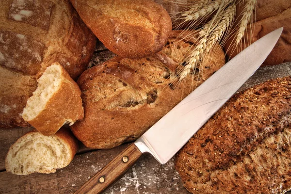 A selection of bread loaves with knife — Stock Photo, Image