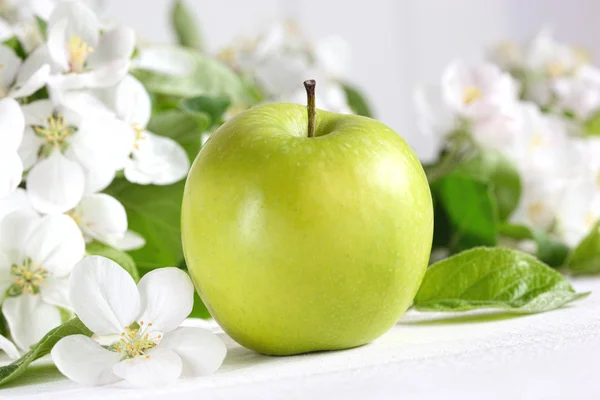 Green apples with blossoms on table — Stock Photo, Image