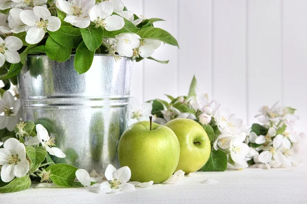 Green apples with blossoms on table — Stock Photo, Image